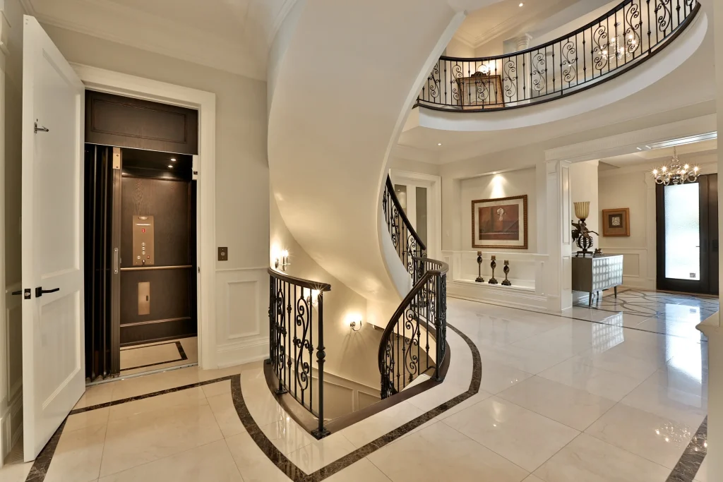 Curved staircase with custom railings featuring the in-home elevator.‎