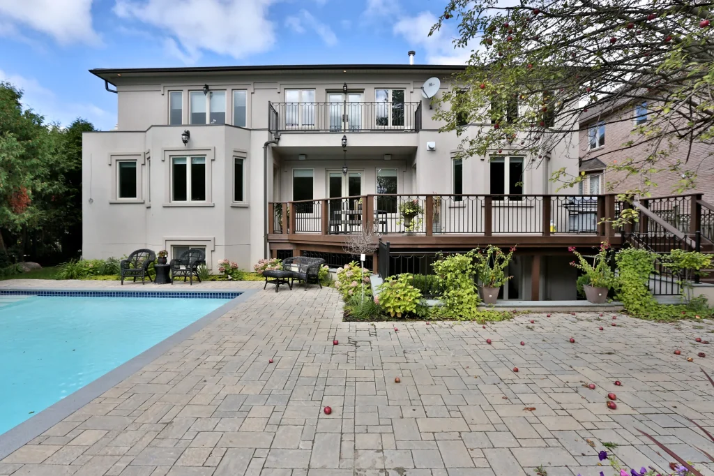 Contemporary suburban home with large wrap around patio deck and in-ground pool in backyard
